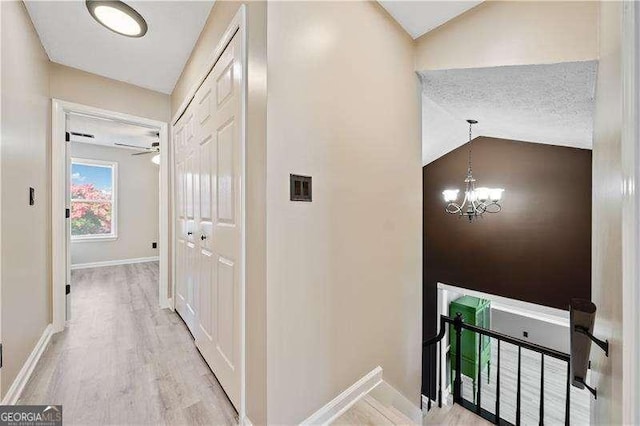 hall with lofted ceiling, an inviting chandelier, and light hardwood / wood-style flooring