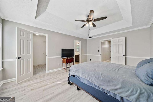 bedroom featuring wood-type flooring, a textured ceiling, ornamental molding, a raised ceiling, and ceiling fan