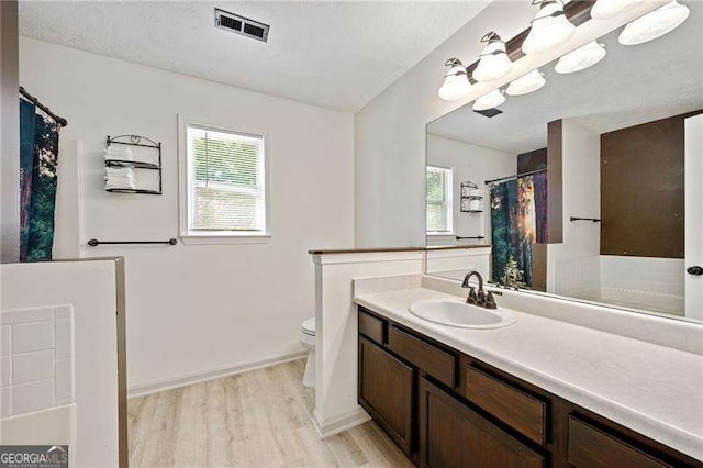 bathroom featuring vanity, wood-type flooring, plenty of natural light, and toilet