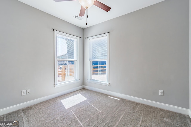 carpeted spare room with a ceiling fan, baseboards, visible vents, and a wealth of natural light