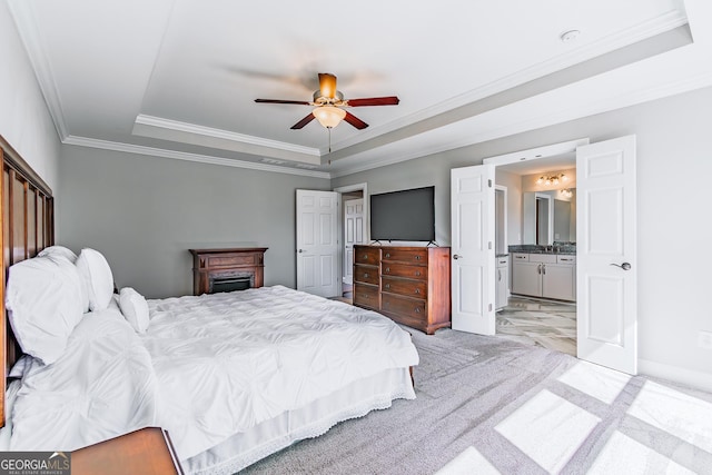 bedroom featuring ceiling fan, ensuite bathroom, light carpet, ornamental molding, and a raised ceiling