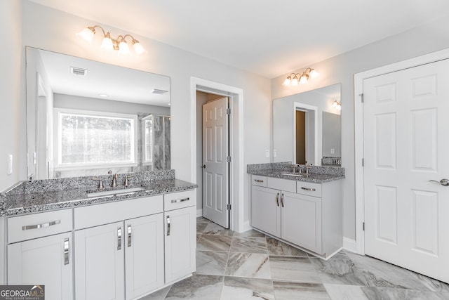 full bath featuring marble finish floor, two vanities, a sink, and visible vents