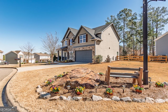 view of front of house featuring driveway, stone siding, a garage, and fence