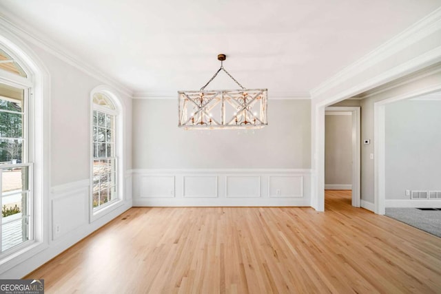 unfurnished dining area with hardwood / wood-style flooring, ornamental molding, and a chandelier