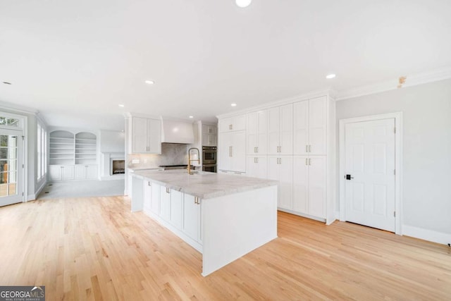 kitchen with white cabinetry, a large island, and light hardwood / wood-style flooring