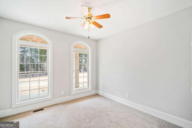 carpeted spare room featuring ceiling fan and a healthy amount of sunlight