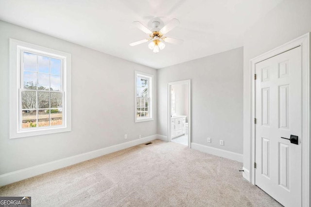 unfurnished bedroom with light carpet, ceiling fan, and ensuite bathroom