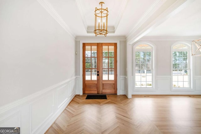 doorway to outside with french doors, a raised ceiling, light parquet floors, and a wealth of natural light