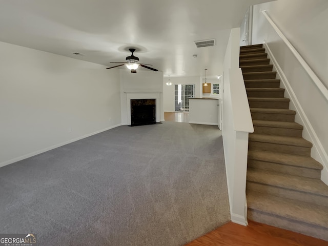 unfurnished living room with ceiling fan, a premium fireplace, and carpet flooring