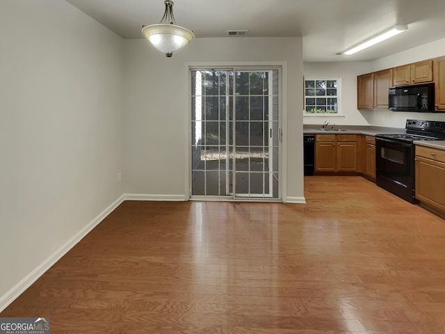 kitchen featuring sink, decorative light fixtures, light hardwood / wood-style floors, and black appliances