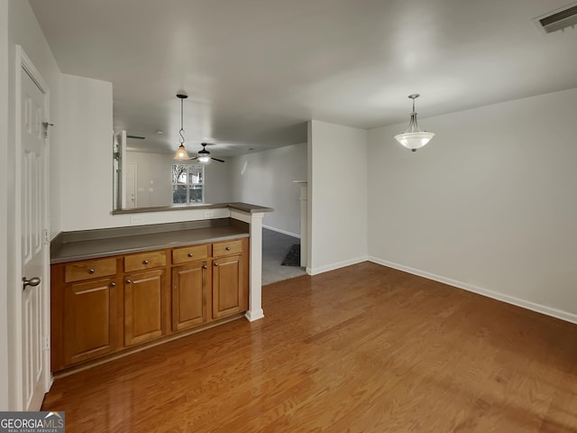 kitchen featuring hardwood / wood-style flooring, kitchen peninsula, ceiling fan, and decorative light fixtures