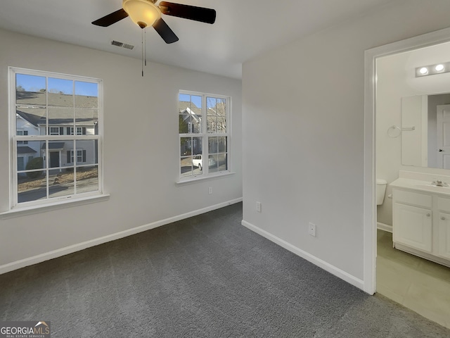 unfurnished bedroom featuring sink, ceiling fan, and dark colored carpet