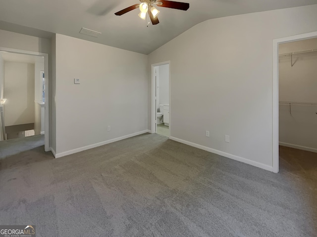 unfurnished bedroom featuring a spacious closet, vaulted ceiling, a closet, and carpet