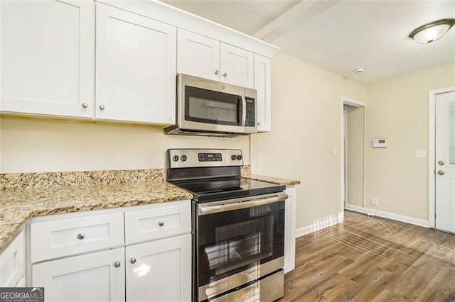 kitchen with light stone countertops, white cabinetry, appliances with stainless steel finishes, and wood-type flooring