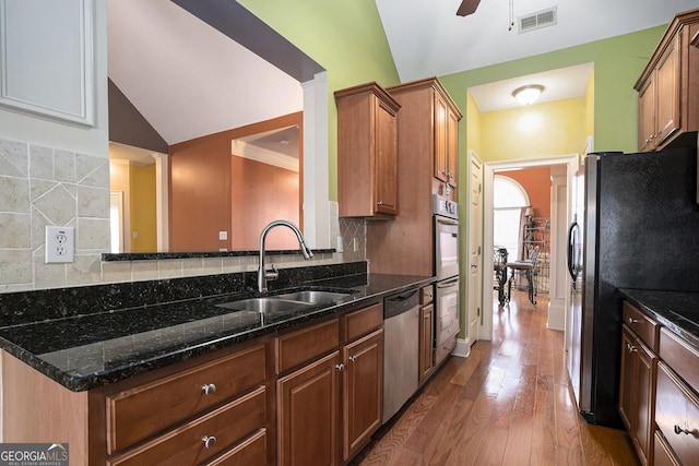 kitchen featuring appliances with stainless steel finishes, sink, lofted ceiling, and dark stone counters