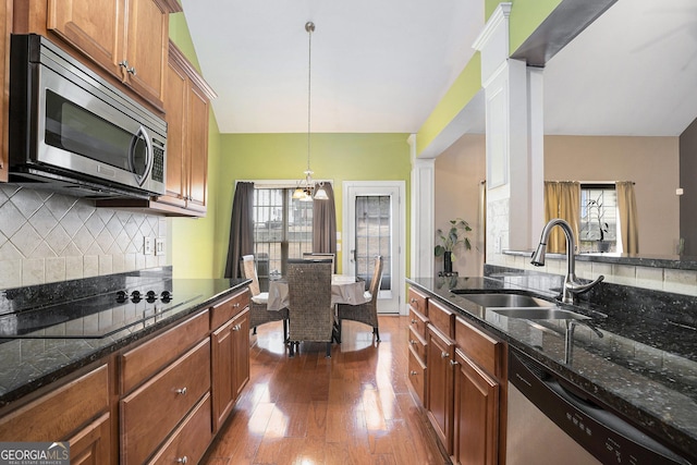 kitchen featuring appliances with stainless steel finishes, pendant lighting, tasteful backsplash, sink, and dark hardwood / wood-style flooring