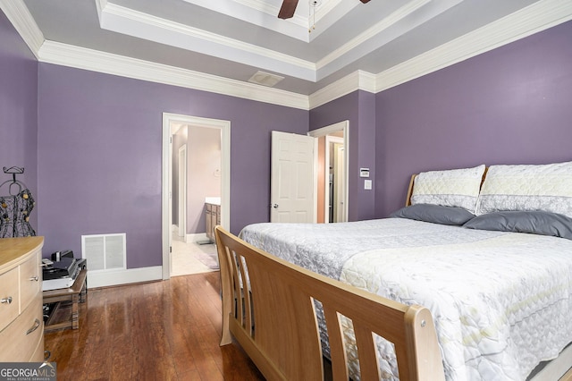 bedroom featuring ceiling fan, dark hardwood / wood-style floors, connected bathroom, a tray ceiling, and ornamental molding