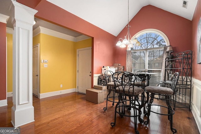 dining room featuring an inviting chandelier, wood-type flooring, vaulted ceiling, and ornate columns