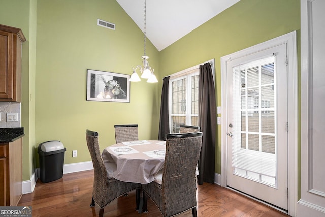 dining room featuring lofted ceiling, dark hardwood / wood-style flooring, and an inviting chandelier