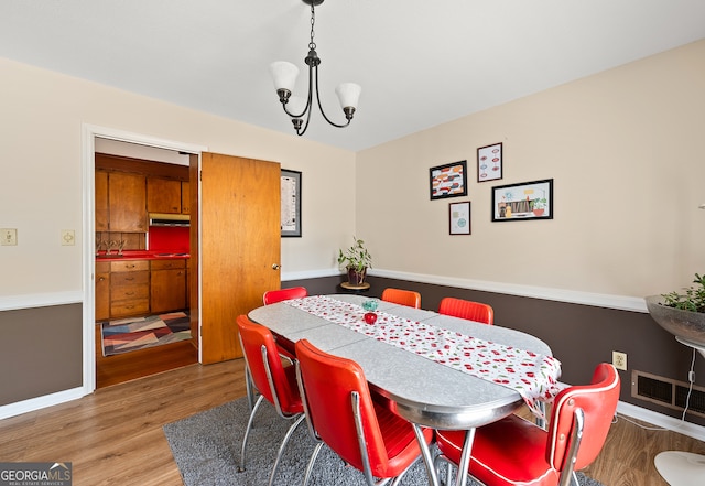 dining space featuring wood-type flooring and a notable chandelier