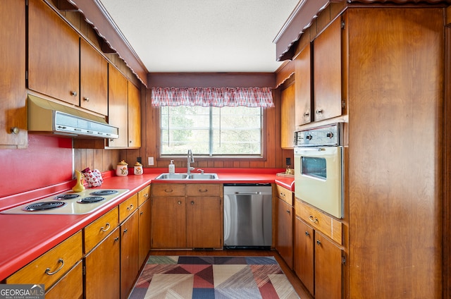 kitchen with cooktop, sink, a textured ceiling, stainless steel dishwasher, and white oven