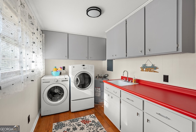 laundry area featuring sink, hardwood / wood-style flooring, washing machine and dryer, and cabinets