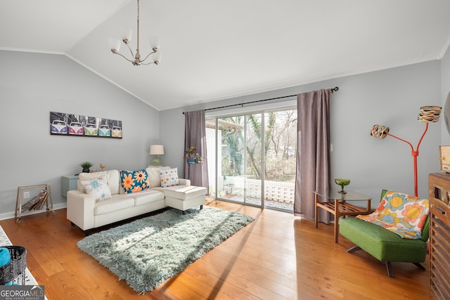 living room featuring lofted ceiling, hardwood / wood-style floors, ornamental molding, and an inviting chandelier