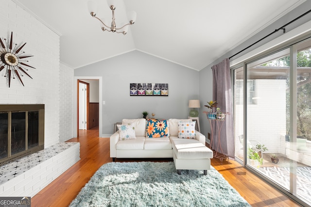 living room featuring lofted ceiling, a chandelier, a fireplace, and light hardwood / wood-style floors