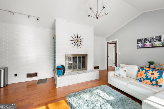 living room featuring brick wall, wood-type flooring, vaulted ceiling, and a brick fireplace