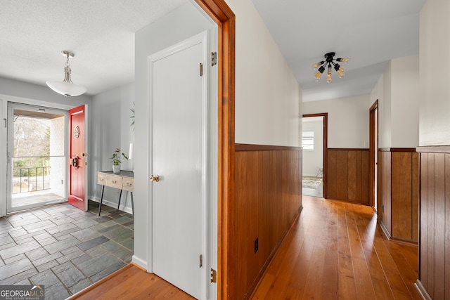 corridor featuring wood-type flooring, wooden walls, and a wealth of natural light