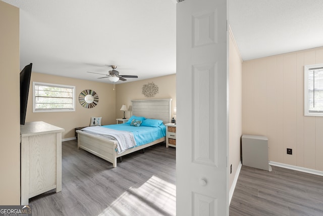 bedroom with multiple windows, hardwood / wood-style flooring, and ceiling fan