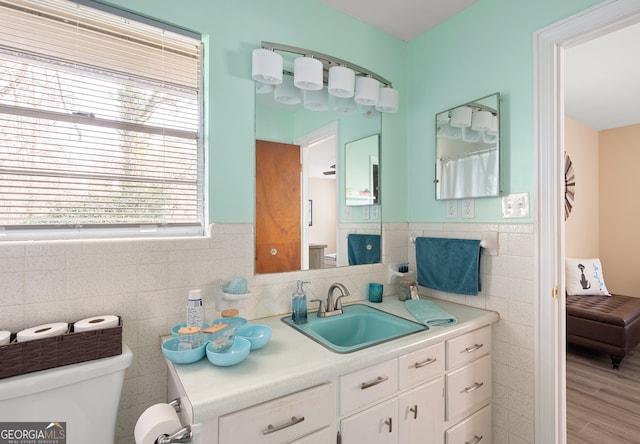 bathroom featuring hardwood / wood-style flooring, vanity, toilet, and tile walls