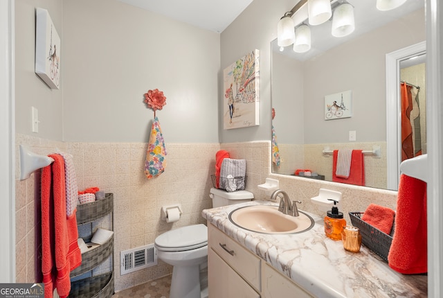 bathroom featuring vanity, toilet, and tile walls