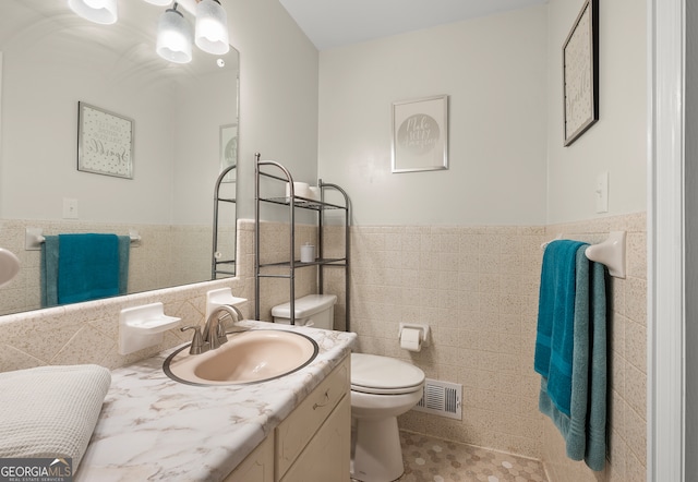 bathroom with vanity, tile walls, tile patterned floors, and toilet