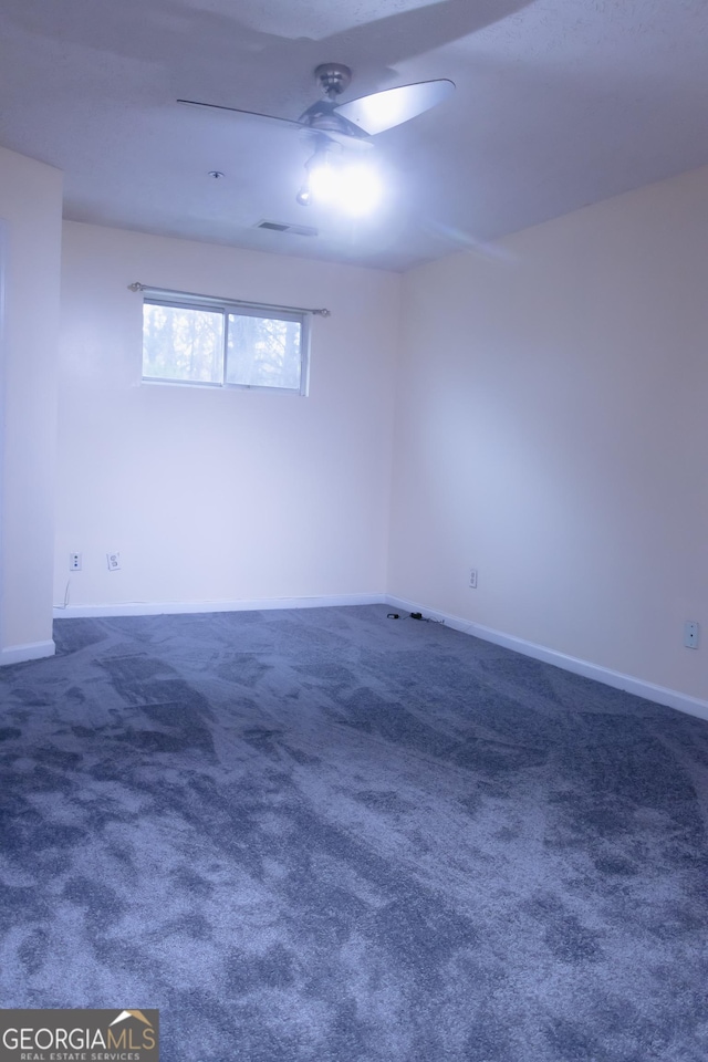 empty room with dark colored carpet and ceiling fan