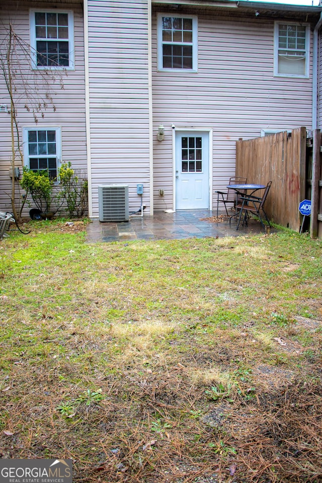 rear view of house featuring central AC unit, a lawn, and a patio area