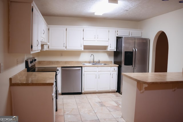 kitchen with a kitchen bar, sink, white cabinetry, a textured ceiling, and appliances with stainless steel finishes