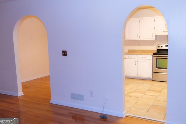 kitchen with white cabinets, stainless steel range with electric cooktop, and light wood-type flooring