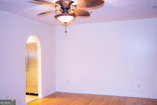 unfurnished room with ceiling fan, light hardwood / wood-style flooring, and a textured ceiling