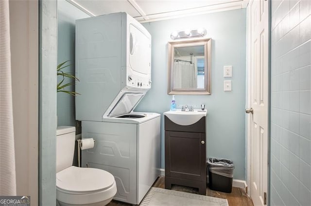 bathroom featuring vanity, stacked washer and dryer, hardwood / wood-style floors, and toilet