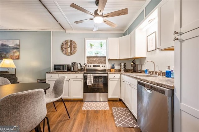 kitchen featuring sink, ceiling fan, appliances with stainless steel finishes, light hardwood / wood-style floors, and white cabinets