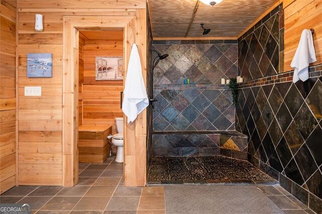 bathroom with a tile shower and wooden walls