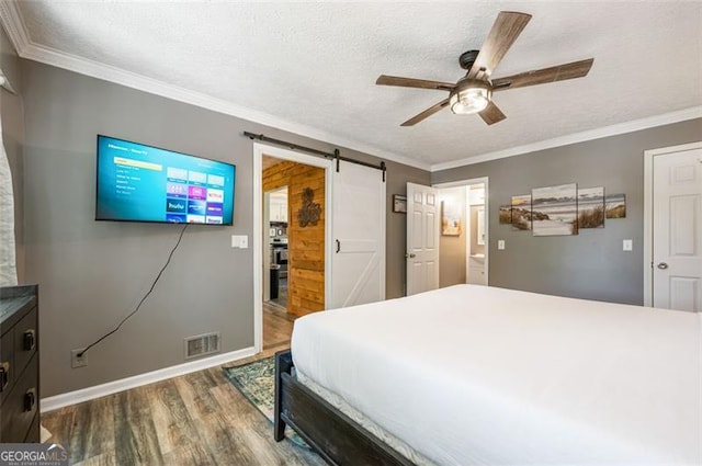 4297 Earney Rd, Woodstock, GA 30188 - bedroom featuring wood finished floors, a barn door, crown molding, ceiling fan, and a textured ceiling