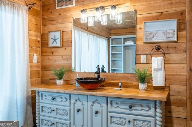 bathroom with vanity and wood walls