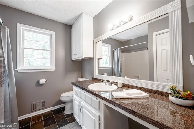 bathroom with vanity, a healthy amount of sunlight, a textured ceiling, and toilet