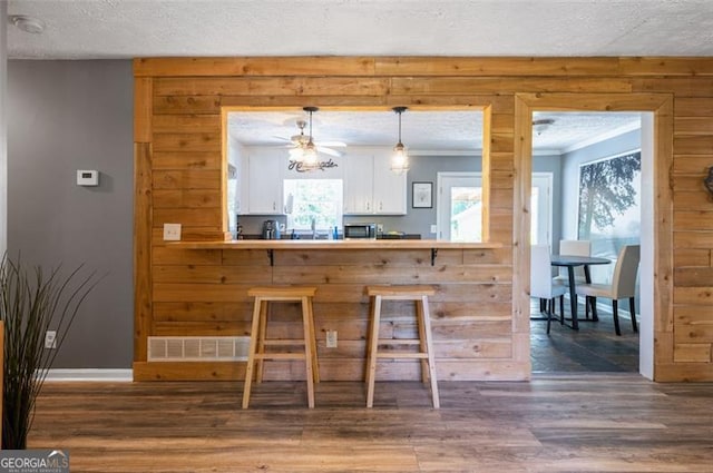 4297 Earney Rd, Woodstock, GA 30188 - kitchen with a textured ceiling, white cabinets, wood finished floors, crown molding, and hanging light fixtures