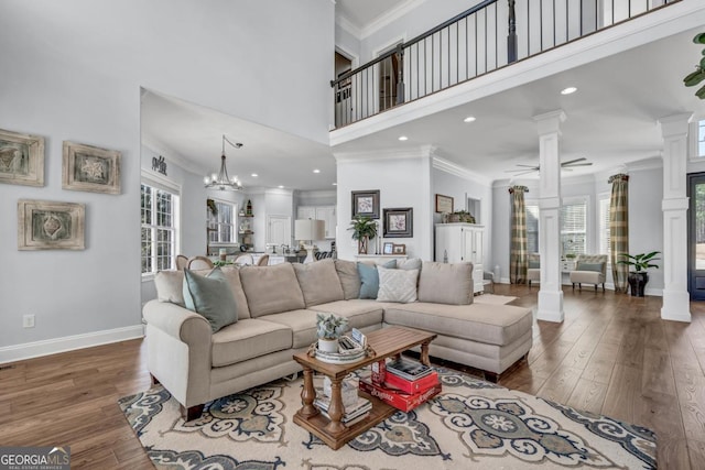 living room featuring a towering ceiling, ornamental molding, dark hardwood / wood-style flooring, and ornate columns