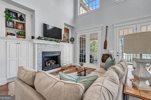 living room featuring hardwood / wood-style floors, a towering ceiling, and a fireplace