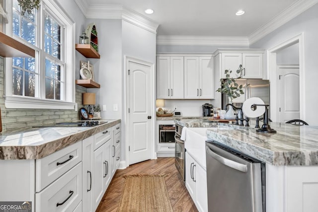 kitchen featuring crown molding, appliances with stainless steel finishes, light stone counters, white cabinets, and light wood-type flooring