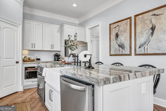 kitchen featuring white cabinetry, ornamental molding, stainless steel appliances, light stone countertops, and light hardwood / wood-style floors